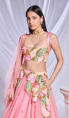 Our pink tulle lehenga is adorned with intricate patchwork embroidery and metallic accents cascading from the waist to the hips. The lehenga is embellished with scatter embroidery, featuring gold elements and delicate pink crystals throughout. Completing the ensemble is a sleeveless pink blouse featuring matching patchwork. Pink Designer Wear Sets With Sheer Dupatta, Pink Organza Choli For Reception, Pink Sharara For Reception And Diwali, Pink Organza Choli With Zari Work, Designer Pink Lehenga With Sheer Dupatta, Pink Bollywood Sets In Organza, Pink Sharara With Sheer Dupatta For Reception, Pink Organza Choli With Resham Embroidery, Pink Bollywood Organza Sets