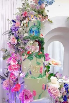 a multi - tiered wedding cake with flowers on it and an elaborate topper