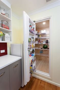 an open refrigerator in a kitchen next to a counter with food items on the shelves