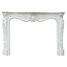 a white marble fireplace mantel with carvings