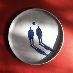 a plate with two people painted on the side and one person standing in front of it