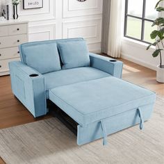 a blue couch sitting on top of a wooden floor next to a white dresser and window