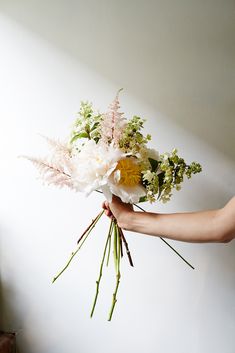 a person holding a bouquet of flowers in their hand with white and yellow accents on it