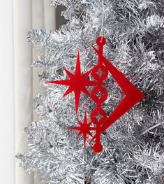 a red ornament hanging from the side of a christmas tree with silver tinsel