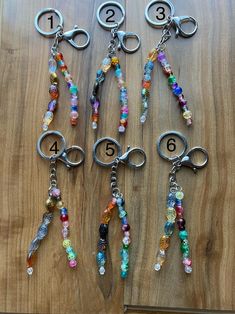 six different types of beaded key chains on a wooden surface with numbers in the middle