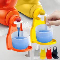 a person is pouring water into two cups in front of an orange and blue machine