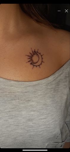 a woman with a small sun and moon tattoo on her upper back shoulder, it is dark