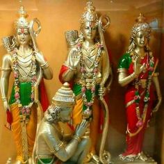 three statues of hindu deities on display in a glass case