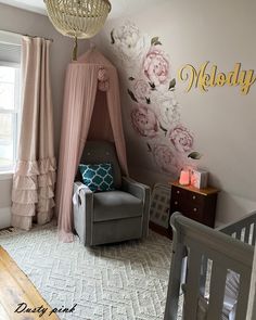 a baby's room decorated in pink and gray with flowers on the wall, crib bedding, and chair