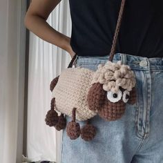 a crocheted sheep purse hanging from the back of a woman's waist