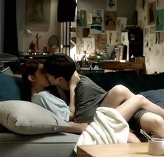 two people laying on a couch kissing each other