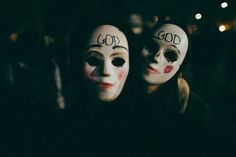 two people wearing masks with the words god written on them in front of their faces