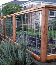 the fence is made of metal wire and has flowers growing on it, along with other plants