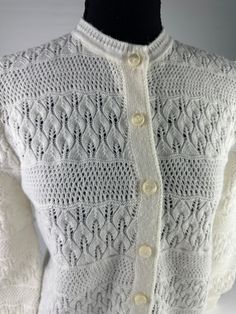 a white knitted sweater with buttons on the collar