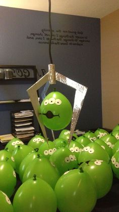 an arrangement of green apples with googly eyes on them in front of a blue wall