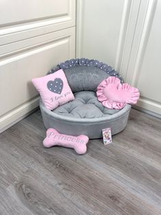 a dog bed with pillows and a bone toy on the floor