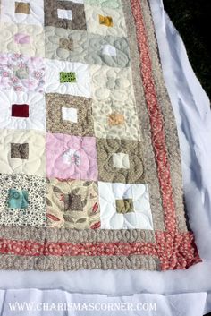 an old quilt is laying on top of a white sheet that has been turned into a table runner