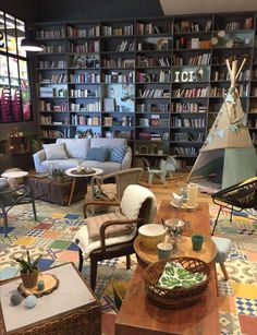 a living room filled with lots of furniture and bookshelves covered in shelves full of books