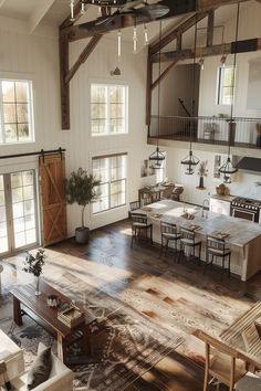 a large open living room and dining area with wood flooring, exposed beams, and white walls