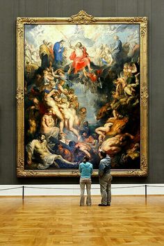 two people standing in front of a large painting