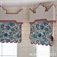 two windows with blue and red curtains hanging from them