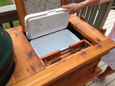 a person is holding an ice chest with tongs and other items in it on a deck