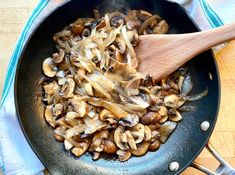 mushrooms being cooked in a skillet with a wooden spoon