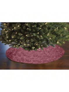 a small christmas tree in a pink pot on a wooden floor with lights around it