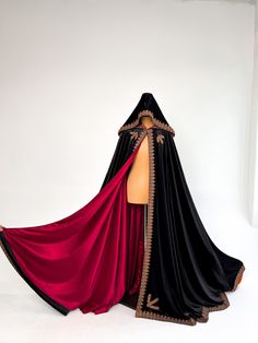 a mannequin dressed in black and red with a cape on it's head