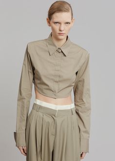 Color: Olive Crisp cotton poplin Fitted silhouette Highly cropped profile Padded shoulders Pointed collar Button front closure Curved hem 100% Cotton Dry Clean By The Frankie Shop. Imported Product Measurements: XS- 15.5" Shoulder, 34" Bust, 13.5" Length S- 16" Shoulder, 36" Bust, 14" Length M- 16.5" Shoulder, 38" Bust, 14.5" Length L- 17" Shoulder, 40" Bust, 15" Length Model is 178cm/ 5'10" wearing size S Chic Collared Cotton Crop Top, Fitted Collared Cotton Crop Top, Fitted Cotton Collared Crop Top, Cotton Cropped Shirt With Spread Collar For Workwear, Cropped Cotton Workwear Shirt, Fitted Cotton Cropped Shirt For Work, Cropped Cotton Shirt With Spread Collar For Workwear, Cotton Button-up Crop Top, Fitted Button-up Cotton Crop Top