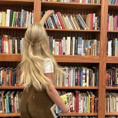 a woman standing in front of a book shelf filled with books