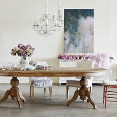 a dining room table with chairs and a chandelier hanging from the ceiling above it