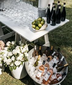 a table topped with lots of bottles of wine and glasses filled with ice next to flowers