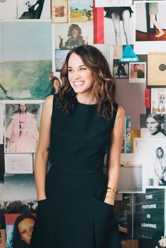 a woman standing in front of a wall full of pictures and posters with her hands on her hips