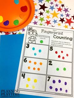 a fingerprint counting game next to a paper plate and some colored stars on the table