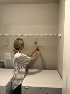 a woman is holding a wrench in front of the washer