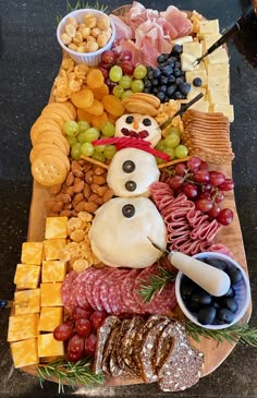 a platter filled with cheese, meats, crackers and grapes