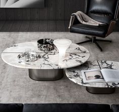 a marble coffee table with two black chairs and a magazine on the floor next to it