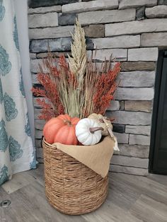 a basket filled with pumpkins, wheat and other autumn decorations next to a fireplace