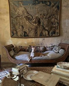 a dog sitting on top of a couch in front of a tapestry