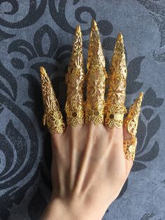 CONTENT:  Full finger armors made of gold colored metal parts.  The set of two hands has 10 full finger armors with long metal claws, 6 are composed of three joints (for long fingers, index, middle, ring) and 4 of only two (thumb and little finger) to be the most comfortable to wear.  Choose your quantity, a single jewel for a finger, by 5 for a complete hand or by 10 for both hands!  Style 1 is made up of 3 pieces marking the 3 joints of the finger, the center piece being in the shape of a flower.  The armors are fully adjustable to the wearer by slightly bending the parts that compose them, one size, suitable for all genres and all styles according to your desires.  This piece is a best seller in my shop, you can wear it in a costume setting, for a wedding, festival, convention or any ev Arrow Nails, Finger Armor, Metal Claws, Claw Rings, Long Fingers, Nail Rings, Nail Guards, Claw Gloves, Double Rings