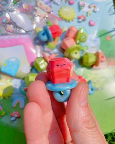 a hand holding a small toy car in front of a table with other toys on it