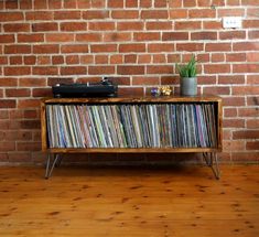 an old record player sitting on top of a wooden shelf next to a brick wall