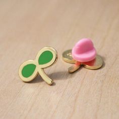 a pair of green and gold cufflinks with a pink button sitting on top of it