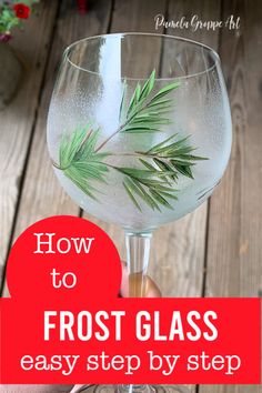 a hand holding a glass filled with water and green leaves on top of it, text overlay reads how to frost glass easy step by step