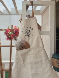 a white apron hanging from the side of a wooden rack with a bottle in it