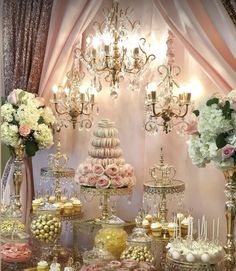 a table topped with lots of desserts next to a chandelier