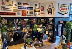 the inside of a clothing store with lots of signs on the wall and plants in pots