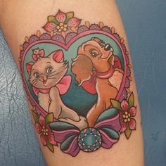 a cat and dog tattoo on the leg with flowers in the shape of a heart