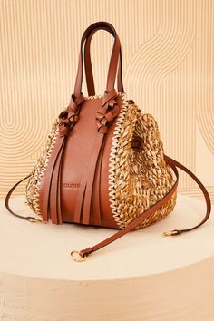 Beige Bucket Bag With Intrecciato Weave For Vacation, Beach Bucket Bag With Intrecciato Weave, Brown Intrecciato Weave Straw Bag For Beach, Brown Straw Bag With Intrecciato Weave, Chic Brown Straw Bag With Intrecciato Weave, Luxury Straw Crossbody Bag For Vacation, Luxury Brown Bucket Bag For Beach, Luxury Brown Bucket Bag For The Beach, Shape Silhouette